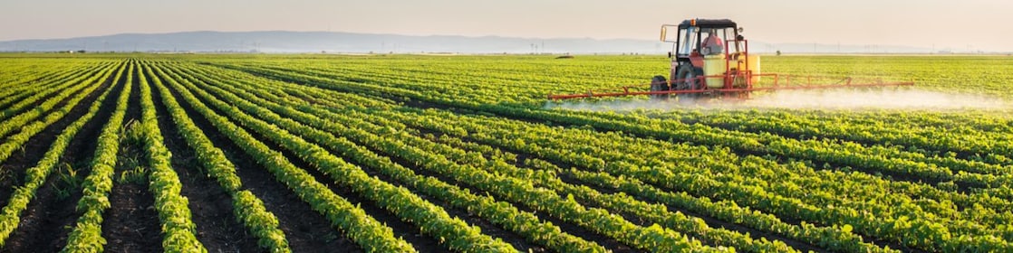 Farmer spraying his plants on a farm using a water sprayer tractor