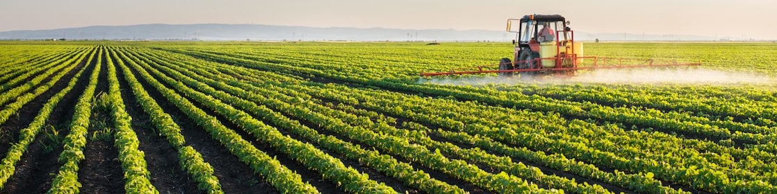 Farmer spraying his plants on a farm using a water sprayer tractor