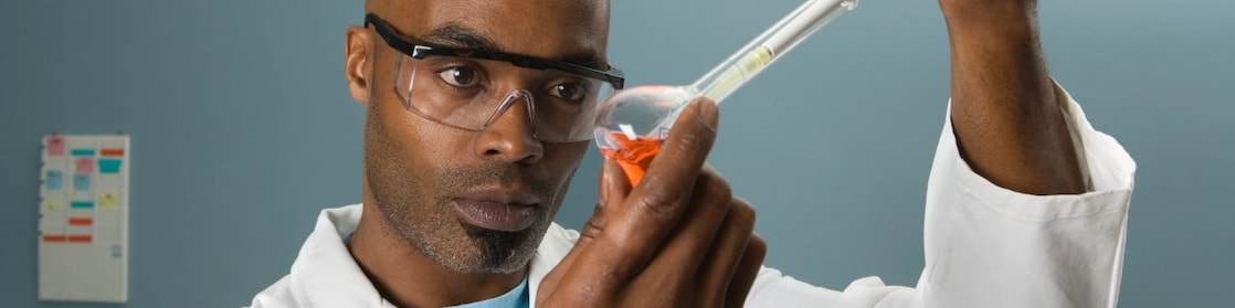 Male laboratory technician holding a flask and pipette testing diesel