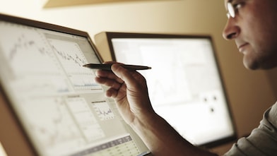 Indian man looking at different price trends on a computer screen