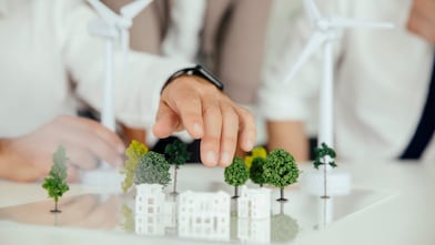 Modern buildings surrounded by trees and wind turbines illustrating sustainability on a scale model