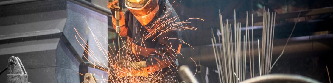 A boiler maker fabricating steel using a flame cutting torch to cut pieces and bend the pieces into shape