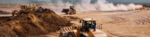 Two bulldozers and a backhoe loader removing waste rock on a mining site