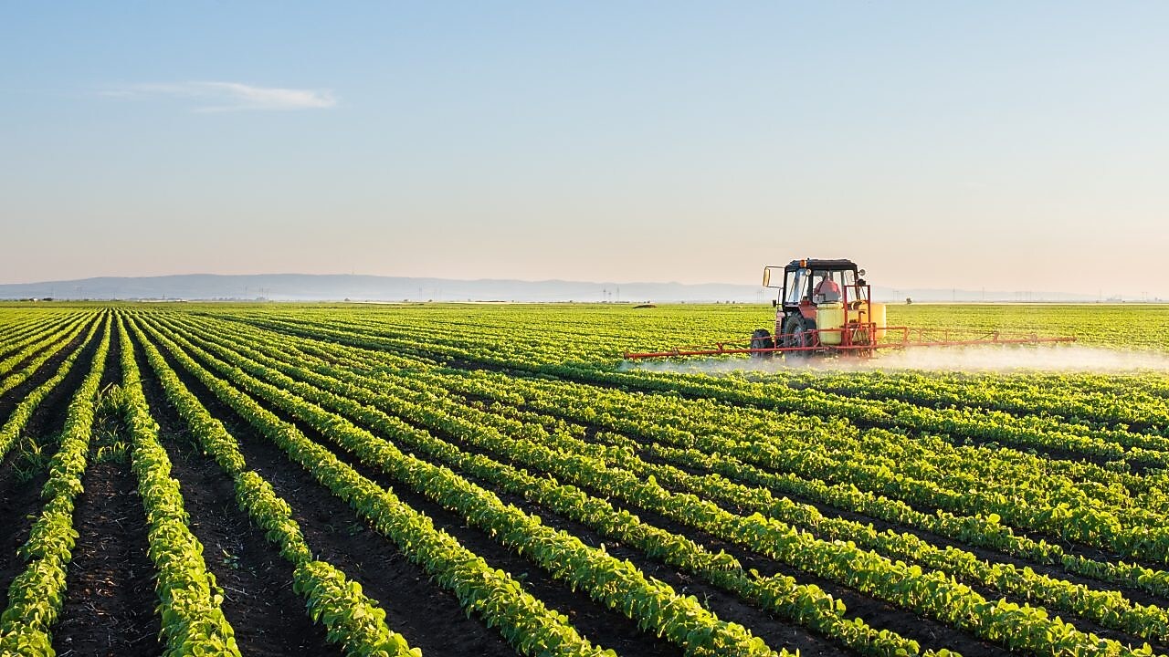 Farmer spraying his plants on a farm using a water sprayer tractor