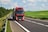 Red truck driving on asphalt road in a rural landscape