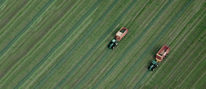 Two tractors in a green field pictured from above
