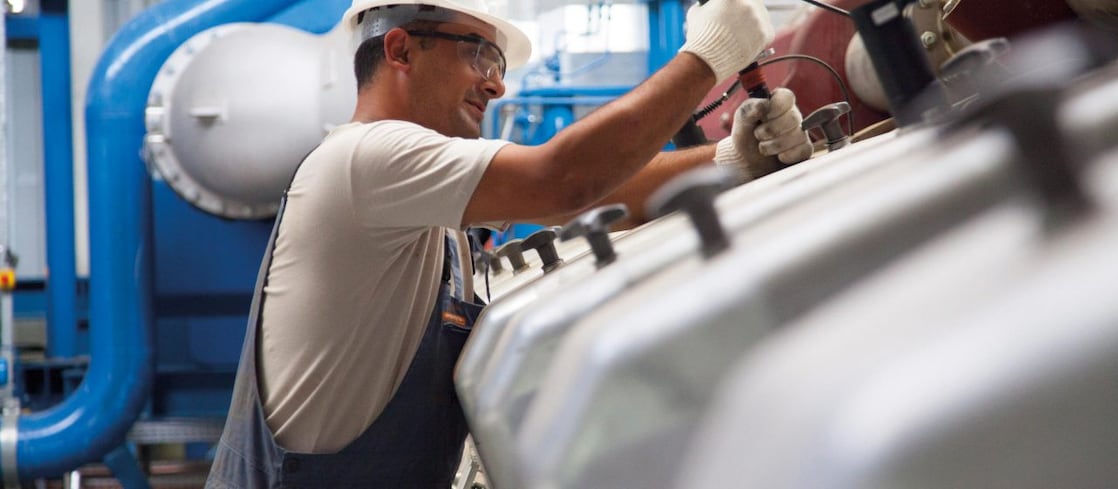 Worker doing maintenance work on a stationary gas engine