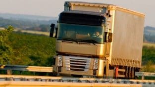 Truck driving on highway, green country background