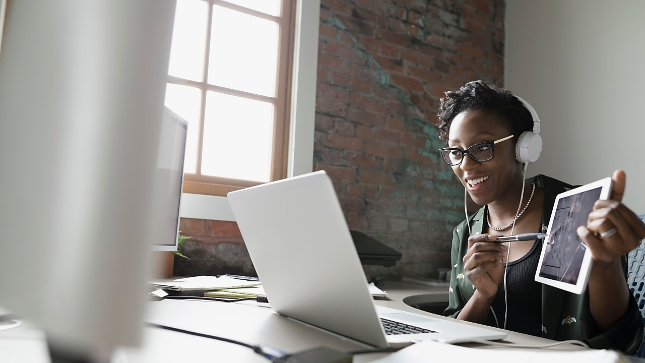 Young woman in a virtual meeting sharing progress of a project on tablet screen