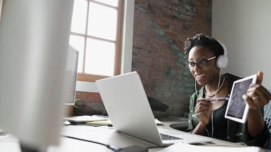 Young woman in a virtual meeting sharing progress of a project on tablet screen