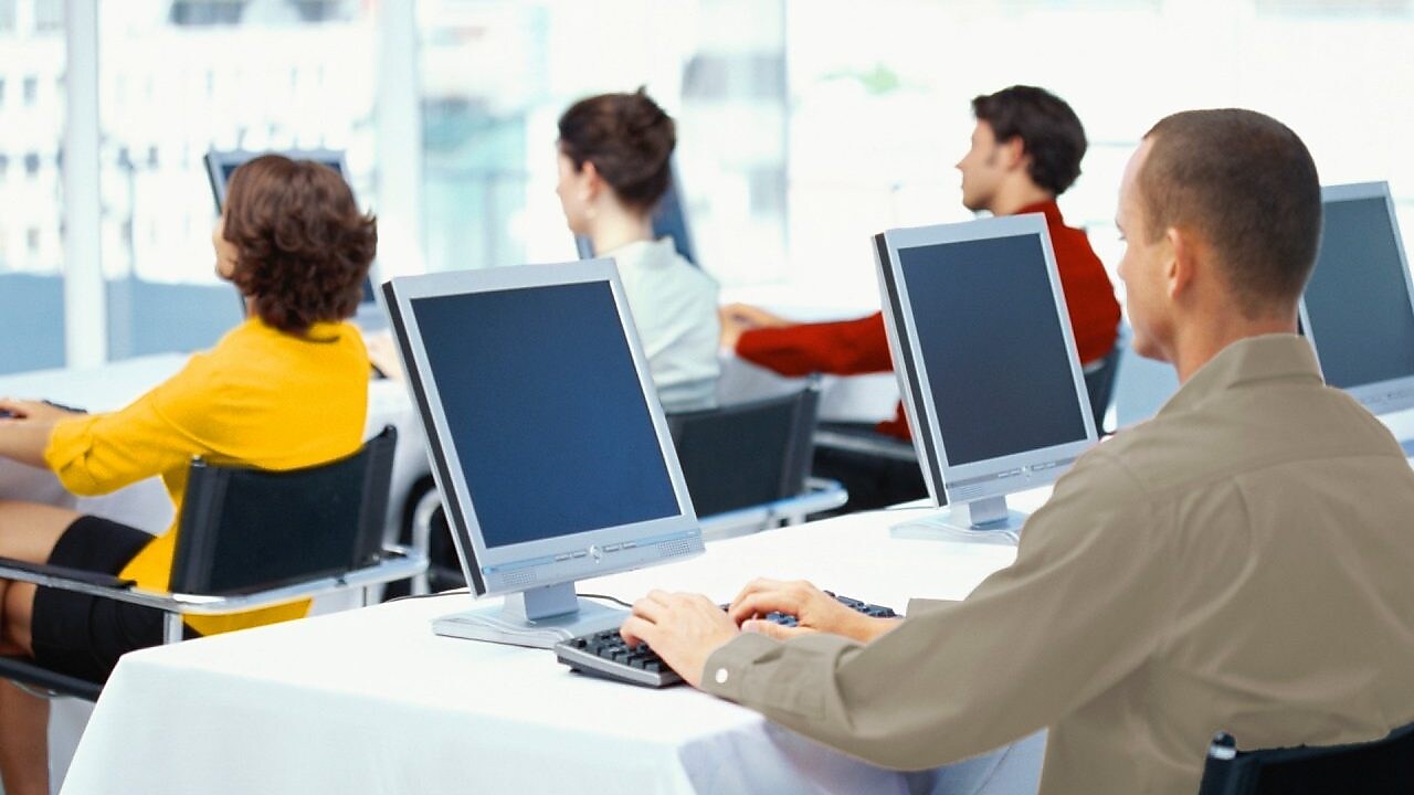  Rear view of four business executives using computers in an office