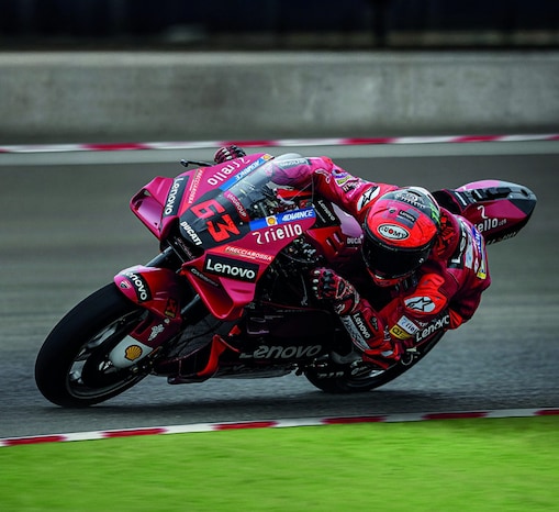 A red Ducati MotoGP bike taking a sharp turn on a race track