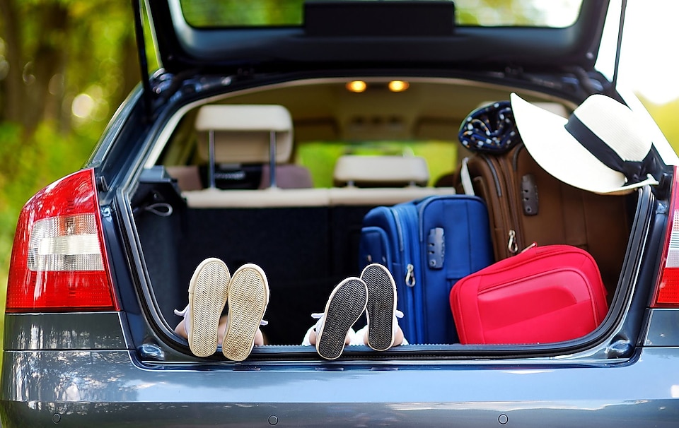 Car with trunck open and the bottom of kids shoes and luggage