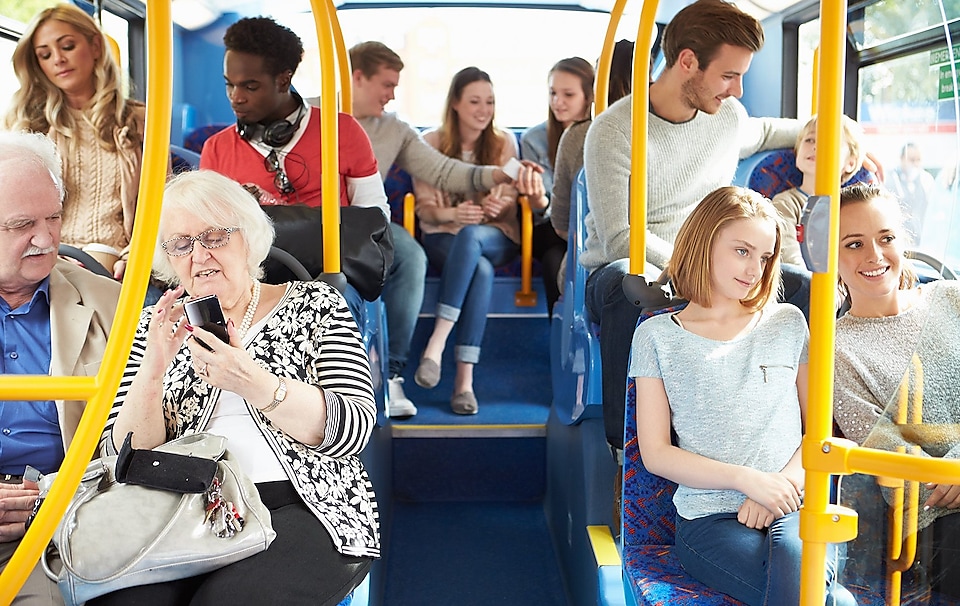 Public bus with a mixture of young and old people all looking happy